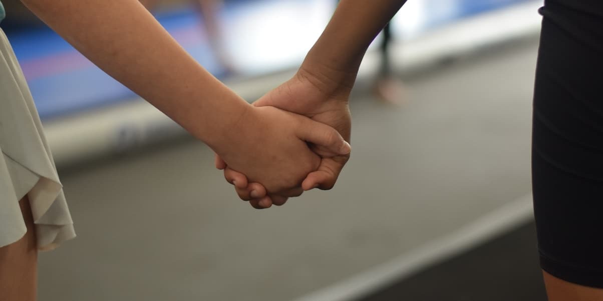 Two Flipping O.U.T. tumblers holding hands on the gym floor